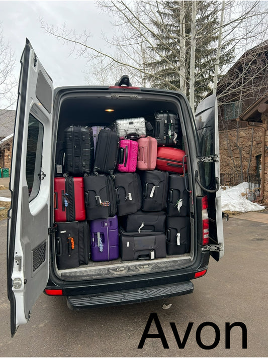 Mercedes Sprinter Van with open rear door filled with suitcases, parked outside of a mansion at Avon Beaver Creek resort.